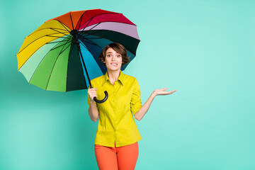 Photo portrait of nervous girl biting lip under colorful parasol isolated on vivid teal color background with copyspace © deagreez