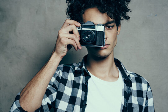 handsome guy with a camera near his face and curly hair plaid shirt hobby photographer