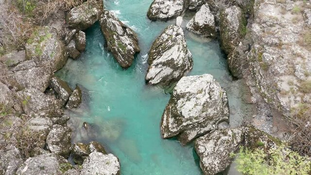 Wild green stream flowing through rocky canyon with white water rapids. Fresh waters of clean turquoise mountain river - natural resources and environmental protection - conservation. Aerial top view.