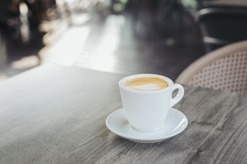 Cup of coffee with latte art on rustic wooden table.