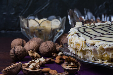 Obraz na płótnie Canvas Delicious cake with nuts, almonds, black and white chocolate on a dark background side view copy space, close up