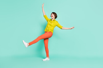 Full length body size photo of dancing on floor girl kicking smiling isolated vibrant turquoise color background