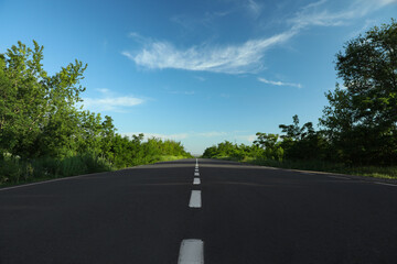 Asphalt road running through countryside on sunny day