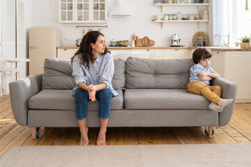 Fototapeta premium Disappointed female after discord and argument with naughty son look at boy with tears in eyes. Young mom offended dissatisfied with disrespectful kid attitude. Upset mother after quarrel and conflict