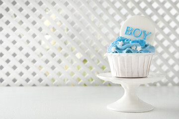 Delicious cupcake with light blue cream and Boy topper on white table, space for text. Baby shower party
