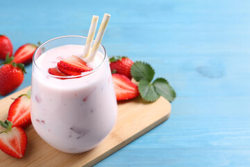 Delicious drink with strawberries on light blue wooden table, space for text