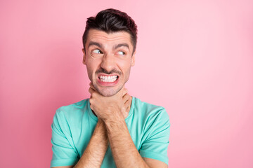 Photo of young unhappy aggressive angry furious man look copyspace choke himself isolated on pink...