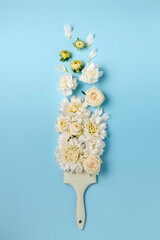 Creative layout made of paint brush and white flowers and on pastel blue background. Minimal flowers composition. Flat lay, top view.