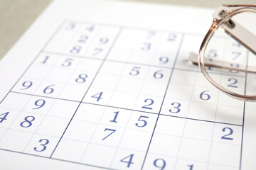 Sudoku and eyeglasses on table, closeup view