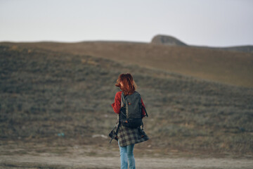 woman traveler in a red jeans sweater with a backpack on her back Tourist on nature in the mountains