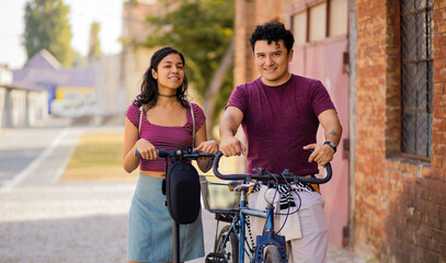 Obraz premium Young couple on the street with bike and electric scooter.