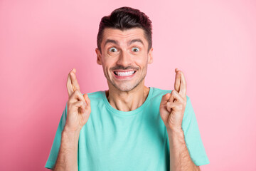 Photo of young excited man happy positive smile crossed fingers expect wish luck isolated over pink...