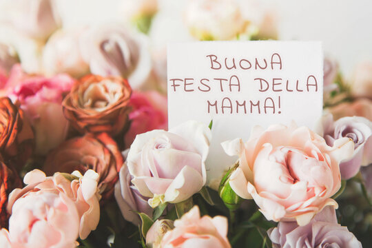 beautiful bright bouquet of colorful roses with white card with the inscription happy mothers day in italian Buona festa della mamma , concept of congratulations on the holiday