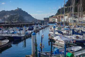 Obraz premium San Sebastian, Spain - April 2, 2021: Boats in the marina in La Concha Bay at the foot of Mt. Urgull