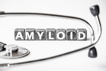 Stone block form word AMYLOID with stethoscope. White background. Medical concept. protein, collects in tissues when diseases, Alzheimer's disease