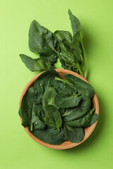 Bowl of spinach leaves on green background