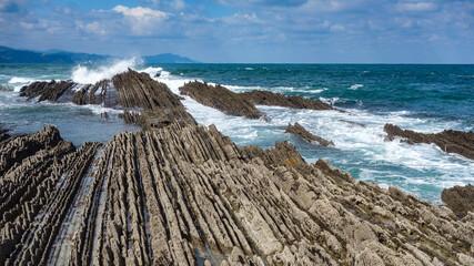 Naklejka premium Zumaia, Spain - March 17, 2021: Flysch rock formations on the beach in Zumaia, Basque Country, Spain