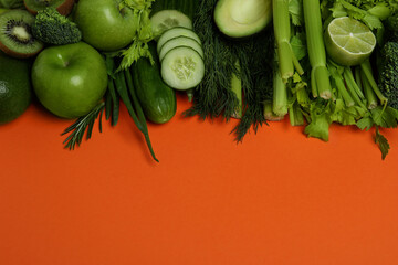 Fresh green vegetables on orange background, space for text