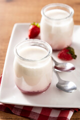 Panna cotta dessert with strawberry on wooden table.