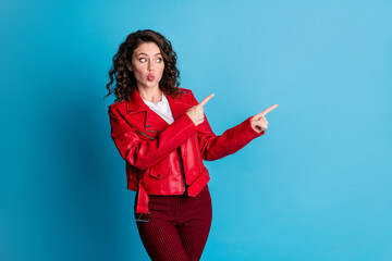 Fototapeta na wymiar Portrait of impressed girl point empty space blow kiss wear red jacket trousers isolated on blue color background
