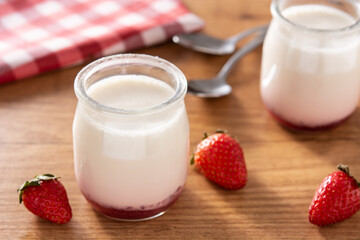 Panna cotta dessert with strawberry on wooden table.