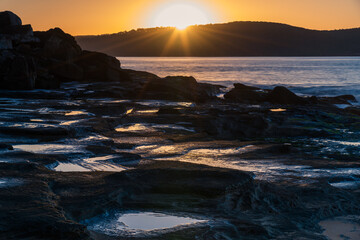 Obraz premium Sunrise seascape, rock platform and sunburst
