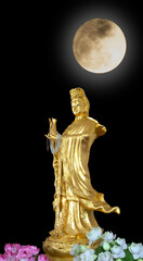 Golden GuanYin statue in Buddhist Cultural with full moon on black background,