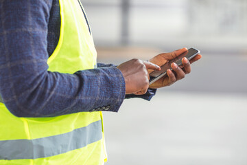 Engineer using a mobile app. Engineer, architect or supervisor in front of a new office building,...