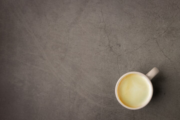 Top view of a cup of hot espresso black coffee with brown espresso coffee foam crema on the top in a white grey pastel ceramic coffee mug put on corner grunge look dark color cement table background.