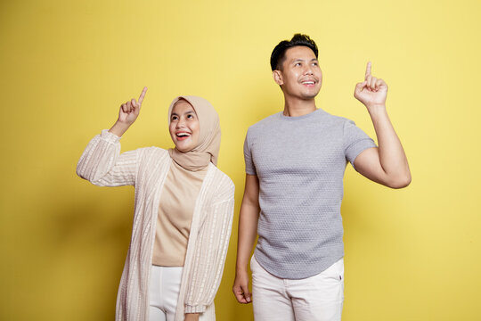 two young, a woman hijab and a man with an expression happy have something good idea together isolated on yellow background