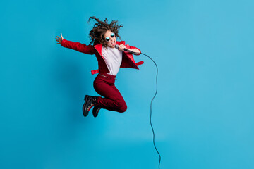 Full size profile photo of carefree lady jump high open mouth sing loud hair flying isolated on blue color background