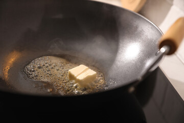 Frying pan with melted butter on stove, closeup