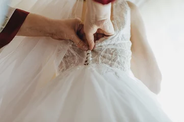 Foto op Plexiglas gathering of the bride, buttoning up a wedding dress close-up, buttons and woman's hands, an unbuttoned dress © Юлия Чернецкая