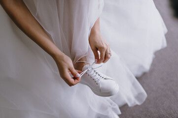 morning of the bride, getting ready, the bride in a wedding dress puts on wedding shoes, legs close-up