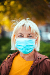 Caucasian adult blond woman 50 years old in bright robe and protective medical respirator mask...
