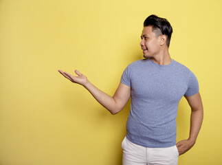 man wearing casual t-shirt smile expression showing blank space isolated on a yellow color background