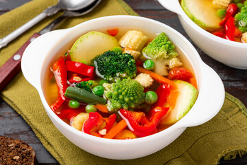 Vegetable soup with broccoli, romanesco, pepper, zucchini, and peas in a white bowl. Vegan soup, diet food.