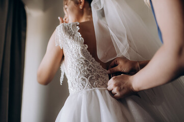 gathering of the bride, buttoning up a wedding dress close-up, buttons and woman's hands, an unbuttoned dress