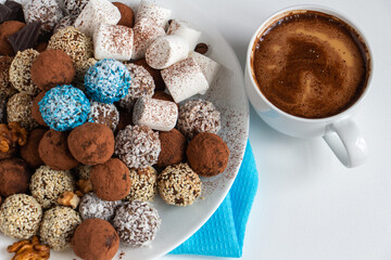 truffles with cocoa, coconut and sesame with chocolate and marshmallows and a cup of aromatic coffee, delicious dessert