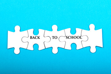 Back to school phrase in 3 pieces paper puzzle on blue background. Education concept.