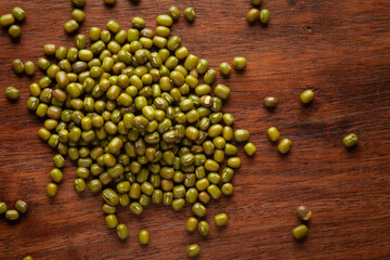 macro Close-up of Organic green Gram (Vigna radiata) or whole green moong dal cleaned on wooden top background.