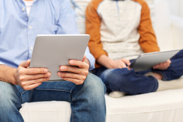 technology, family and people concept - close up of father and son with tablet pc computers at home