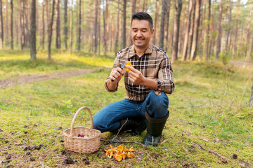 picking season and leisure people concept - happy smiling middle aged man with wicker basket of mushrooms in autumn forest