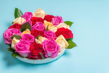 Composition of fresh multicolored roses on ceramic stand