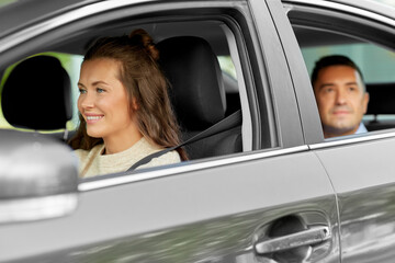 transportation, vehicle and people concept - happy smiling female driver driving car with male passenger