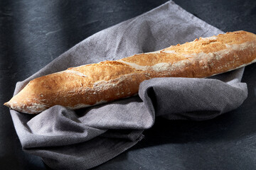 food, baking and cooking concept - close up of baguette bread on kitchen towel