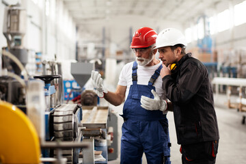 Portrait of workers in factory. Colleagues with helmet working in factory