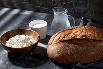 food, baking and cooking concept - homemade craft bread, wheat flour, salt and water in glass jug on table