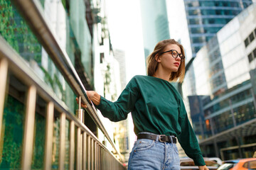 Portrait of a hipster girl with short hairstyle, looking at the side posing on urban street, at...