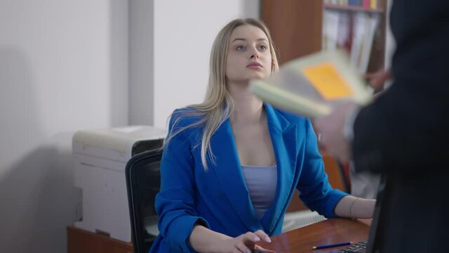 Beautiful young blond woman ignoring CEO scolding and gesturing. Portrait of attractive Caucasian female employee making faces after manager leaving. Business stress and lifestyle